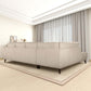 Mid-century modern cream-colored left facing chaise sectional sofa in spacious, elegant living room with natural light and floor-to-ceiling curtains