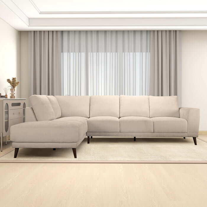 Amara MCM Left Facing Chaise Sectional Sofa in Cream in a modern living room setup with curtains and beige area rug.