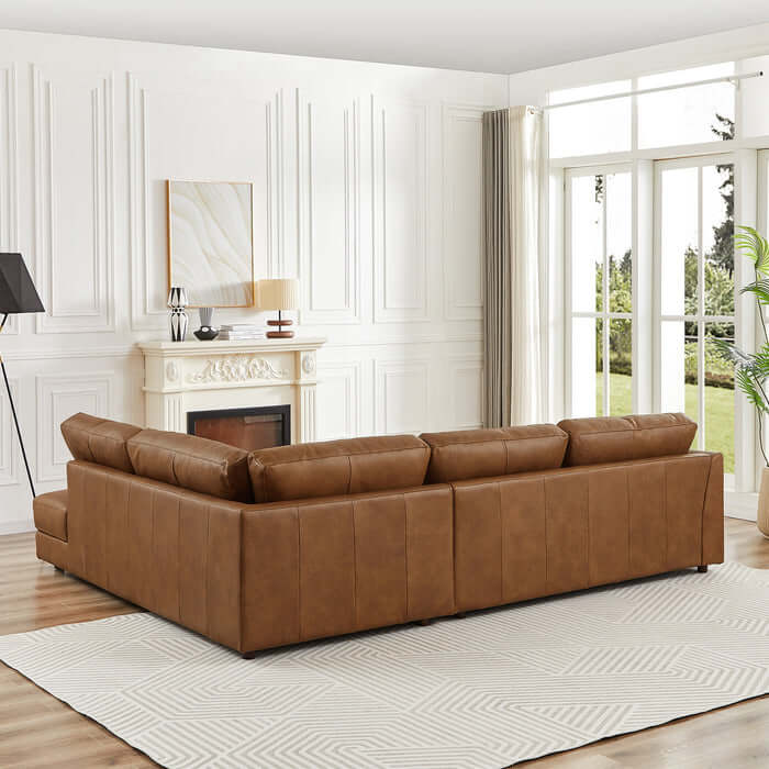 Modern leather sectional chaise sofa in elegant living room with fireplace and large windows.