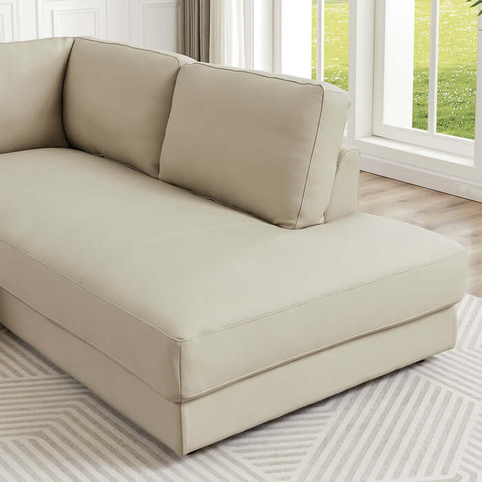 Modern beige leather sectional chaise sofa in stylish living room with natural light.